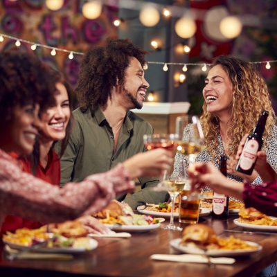 multi-cultural-group-of-friends-enjoying-night-out-eating-meal-and-drinking-in-restaurant-together.jpg